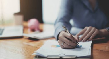 İş kadınlarının el ele tutuştuğu kalem ve mali evraklara işaret ederek, kar konseptlerini analiz etmek için finansal tabloları kapat