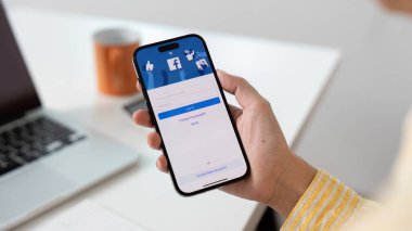 CHIANG MAI, THAILAND JAN 6 2025: Ekranda sosyal internet servisi Facebook 'u olan iPhone 14' ü tutan kadın..
