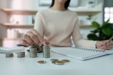 Bir kişi, bütçe ve mali organizasyonun önemini vurgulayarak, bir deftere yazarken madeni paraları sayar.