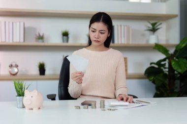 Finansal belge ve paraları inceleyen kadın, modern bir çalışma alanında bütçe ve mali planlamayı yansıtıyor.