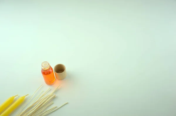 Sarı mumlar ve ahşap sopalarla dolu bir şişedeki turuncu kokulu yağ. Aromaterapi, spa, masaj, rahatlama veya psikolojik refah kavramlarını geliştirme. Kopyalama alanı olan en küçük bileşim.