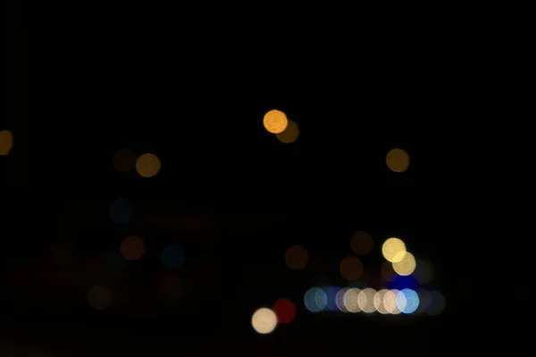 Colored circular blurry bokeh combination of transportation, cars and street lights at the intersection in city. Beautiful blur at dark black night abstract background. Horizontal, frontal shooting.