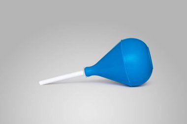 Beyaz plastik uçlu mavi kauçuk lavman, yan yatmış, açık gri arka planda.