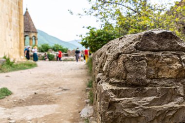 Ananuri kalesinin ortaçağ duvarının bir parçası. Kilisenin bulanık kubbesi ve turist figürleri