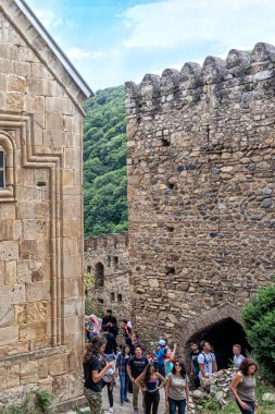 Ananuri, Georgia, 07.20.2019. Gürcistan 'daki Ananuri kalesinin avlusundaki farklı ülkelerden gelen bir grup turist. Kale duvarları, taş gözlem kulesi, kilise duvarı.