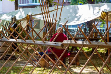 Moskova, Rusya, 08.14.2018. Bornozlu bir animatör, ahşap bir bankta oturuyor savunma çayırının arkasında, şehir parkındaki çimenlikte.