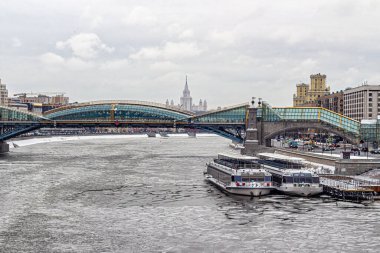 Moskova, Rusya, 29.12.2020. Bogdan Khmelnitsky Moskova Nehri 'nin karşısındaki Kiev tren istasyonunun yanındaki yaya köprüsü. Nehirde, kış otoparkında gemiler var.