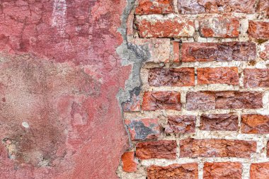 Eski bir tuğla duvarda tuğla işi ve gevşek alçı. Zaman ve kötü hava yüzünden çatlaklar ve tuğla parçaları ortaya çıktı.