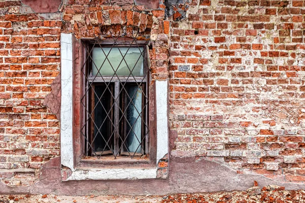 窗户上有生锈的格栅和破碎的玻璃 在一座被毁的废弃房屋残破的砖墙上 — 图库照片