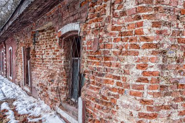 Parmaklıklı pencereleri olan terk edilmiş eski bir evin alçısıyla yıkılan tuğla duvar.