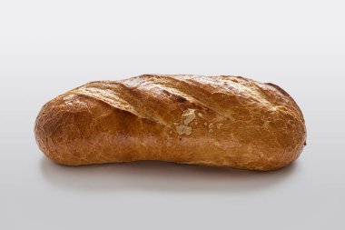 Altın hamurlu ev yapımı ekmek, küçük çatlaklarla kaplı, üzerinde kesikler var, açık arkaplanda.