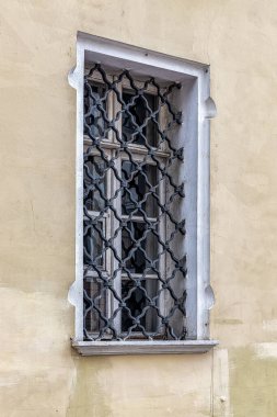 Yaşlı bir tüccarın evinin penceresinde ağır, işlenmiş demir bir ızgara var.