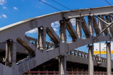 Demiryolu köprüsünün kemerli metal yapısı, perçin, vida ve fındık ile güçlendirilmiş mavi gökyüzüne karşı