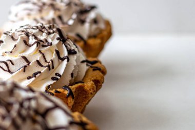 Krem şantili çöreklerden yapılmış tart sepetleri ve hafif bir arka planda, sıvı çikolatayla doldurulmuş.