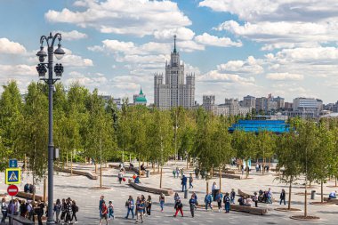 Moskova, Rusya, 05.25.2021. Yeşil yapraklı Zaryadye Parkı manzarası, Kotelnicheskaya seti üzerinde Stalinist gökdelenler ve Kızıl Meydan 'a giden turistler