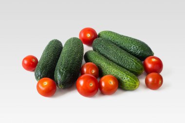 Yeşil salatalık ve küçük kırmızı kiraz domatesleri. Hafif arka planda olgun sebzeler