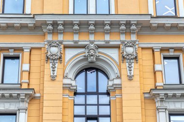 Binanın ön tarafındaki dekoratif pencere, aslan maskesiyle süslenmiş kemer, dekoratif parantez ve çiçeklerle süslenmiş iki adet gül.