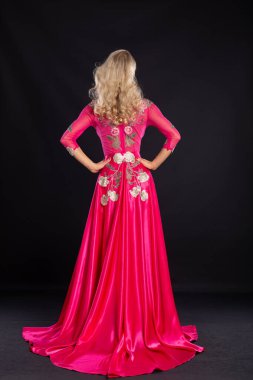 Siyah arka planda pembe seksi elbiseli güzel bir sarışın..