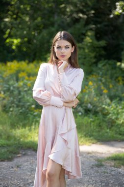 Açık yaz elbisesi içinde güzel bir kadın bir patikada ve arka planda bir orman çayırında.