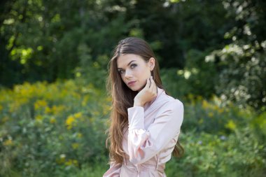 Açık yaz elbisesi içinde güzel bir kadın bir patikada ve arka planda bir orman çayırında.