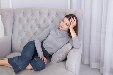 Gri bir kanepede oturan güzel bir esmer.