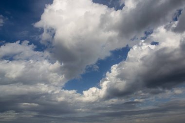 Güneşli bir sonbahar gününde beyaz ve yağmurlu bulutlarla mavi gökyüzü