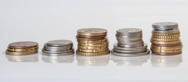 Kredi kartı ve mürekkep kalemi, farklı para birimlerinin banknotları ve sikkelerinin arka planında yatıyor.