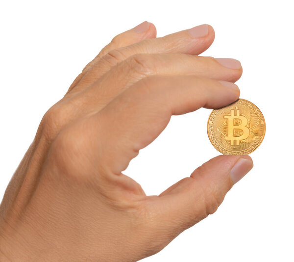 A hand is holding a golden bitcoin coin against a plain background, showcasing its design and shine in bright light.