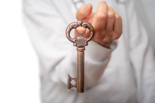Руки держат в руках старомодный ключ, готовый к покупке нового дома, символизирующий надежду и волнение в недвижимости.