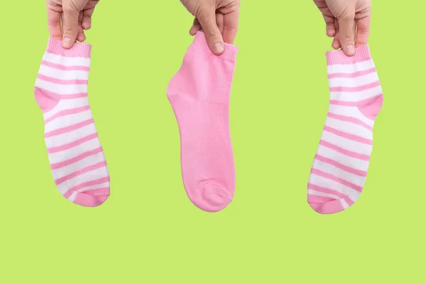 Hand holding three socks in pink color gamma from white to pink close up on green background — Stock Photo, Image