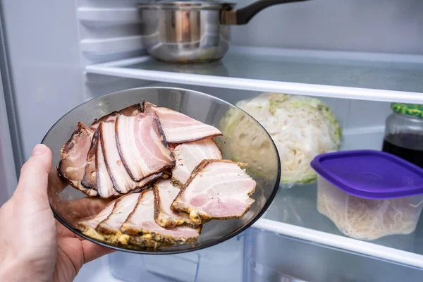 Hand zetten gesneden gekookt vlees, spek in de koelkast voor opslag — Stockfoto