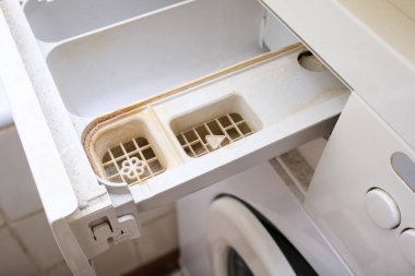 Kirli, küflü çamaşır makinesi deterjanı ve kumaş kremi kutusunun çekmecesini kapat. Küf, pas ve kireç rengi çamaşır makinesi tepsisi. Ev aletleri periyodik bakım