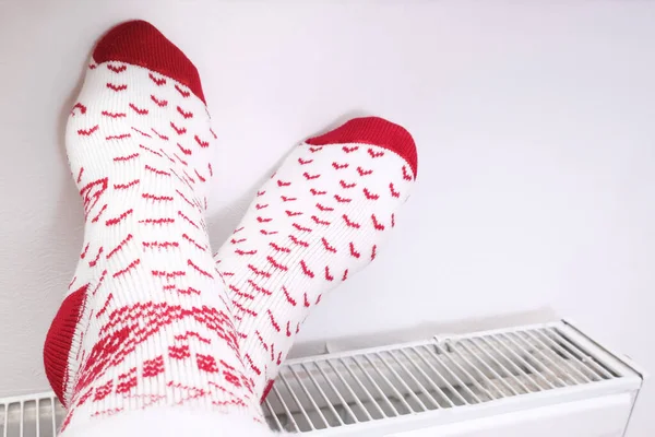 Noel çorapları içinde ayaklar merkezi ısıtıcıda ısınıyor, kış evi dinleniyor ve dinleniyor. — Stok fotoğraf