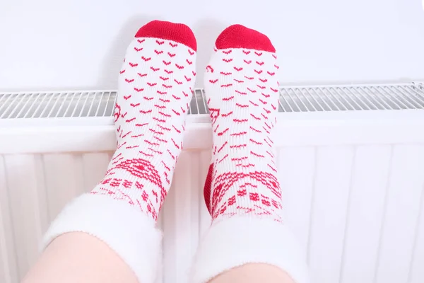 Πόδια σε κάλτσες Χριστούγεννα πάρει ζεστό σε ένα κεντρικό καλοριφέρ θερμότητας, το χειμώνα σπίτι να χαλαρώσετε και να ξεκουραστούν — Φωτογραφία Αρχείου