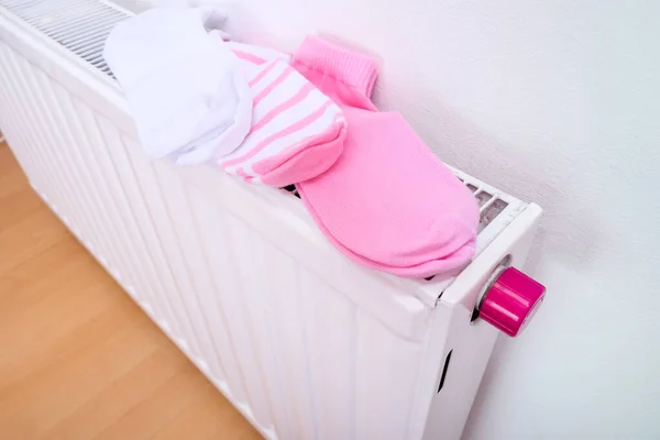 Cotton socks drying on a radiator of central heating, wet clothes hanging on a heater after washing and laundry, clean clothing after wasing machine — Stock Photo, Image