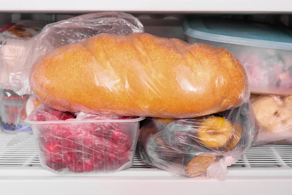 Um pão de pão de trigo e outros alimentos congelados em uma prateleira de um congelador de casa, grande aquisição e armazenamento de alimentos na reserva — Fotografia de Stock