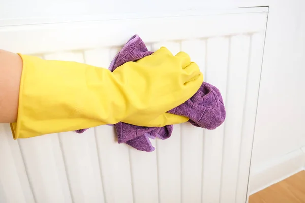 Employee of commercial cleaning company wiping a heater radiator, hand in yellow rubber gloves wiping and washing central heating radiator with microfiber cloth, maid or housewife cares about house — Stock Photo, Image