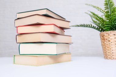 Beyaz bir masanın üzerinde kitap yığını, okuma ve eğitim konsepti