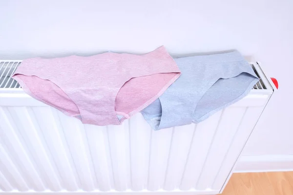 Drying wet underpants on radiator of central heating, casual ladies underwear hanging on a heater, laundry and washing clothes concept — Stock Photo, Image