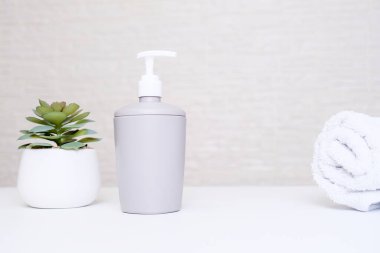 Gri sabun makinesi, beyaz havlu ve spa, vücut ve yüz bakımı için saksı çiçeği, pastel renkte ve fotokopi alanı olan banyo içi.