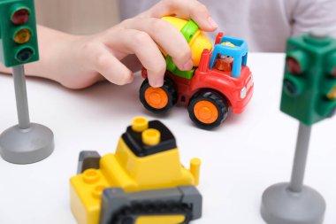 Beyaz bir masada oyuncak araba oynayan bir çocuk.