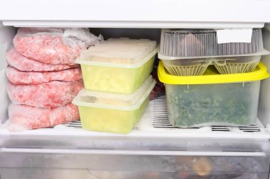 Bir ev dondurucusundaki konteynırlarda birçok farklı dondurulmuş çiğ gıda, et, sebze, ekmek ve semies, mutfak evi rezervleri