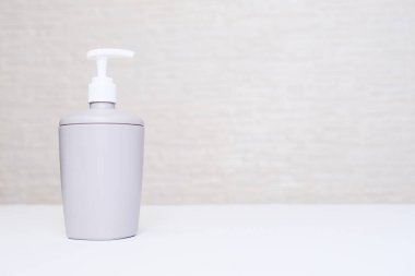 Gri sıvı sabun makinesi, beyaz arka planda bir banyoda fotokopi alanı olan bir şişe.