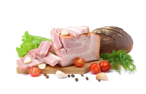 Geräucherter Schweinebauch, Speck, Schinken auf einem Holzbrett mit Kräutern, Tomaten und Schwarzbrot im Hintergrund. Weißer isolierter Hintergrund. — Stockfoto