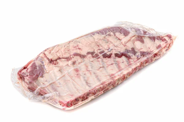 Ένα κομμάτι φρέσκο χοιρινό κρέας σε συσκευασία κενού. Κενή συσκευασία ακατέργαστων νωπών χοιρινών πλευρών που απομονώνονται σε λευκό φόντο. — Φωτογραφία Αρχείου