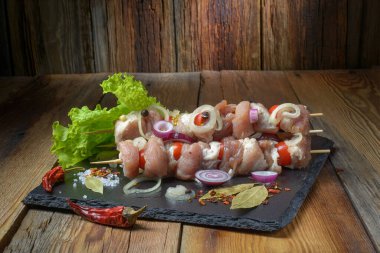 Salamurada çiğ şiş kebap, biber, soğan, körfez kebabı. Domuz şiş kebap, pişirmeye hazır. Eski ahşap bir masa üzerinde..