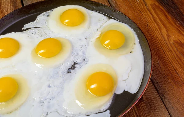 Goreng telur dalam penggorengan di atas meja kayu pedesaan tua, top view. — Stok Foto