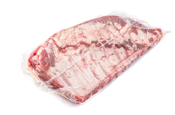 Un trozo de carne de cerdo fresca en un paquete de vacío. Embalaje al vacío costillas de cerdo frescas crudas aisladas sobre un fondo blanco. — Foto de Stock