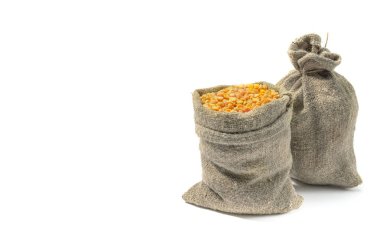 Bezelyeler poşette, beyaz bir arkaplanda izole edilmiş. Bezelyeleri çuval bezelyeye ayır. Sağlıklı yiyecekler. Jute bagette sarı bezelyeler. Odaklanma..