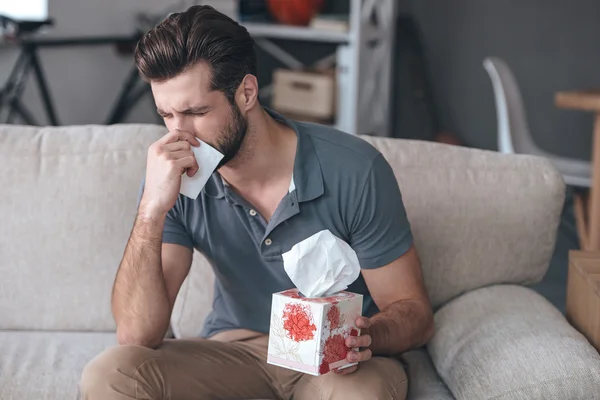 Young man sneezing and using tissue — ストック写真